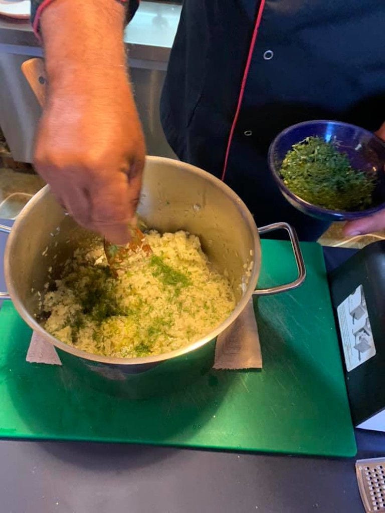 close-up of man cooking and putting salt in the pot with cheese composition at 'Narlis Farm'